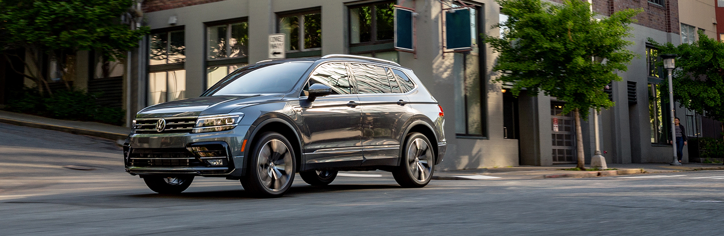 A gray 2020 Volkswagen Tiguan driving in a city intersection.