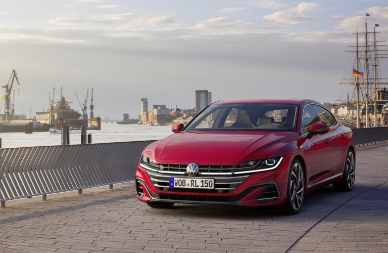 The front image of a red 2021 Volkswagen Arteon parked near water.