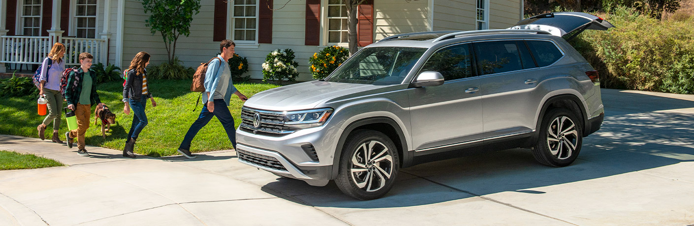 The front and side view of a gray 2021 Volkswagen Atlas parked at a family home.