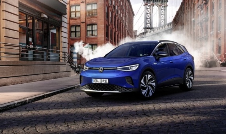 The front of a blue 2021 Volkswagen ID.4 parked in a city area.