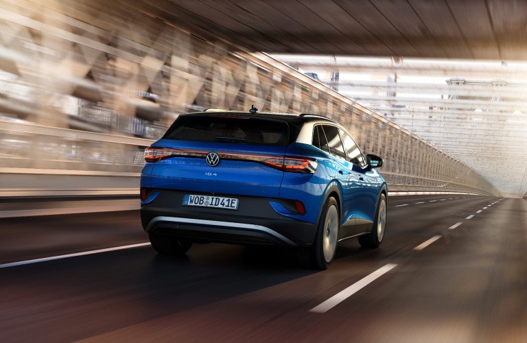 The rear side of a blue 2021 Volkswagen ID.4 driving down a road.
