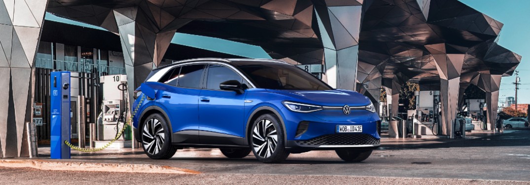 The front side of a blue 2021 Volkswagen ID.4 parked in front of futuristic architecture.