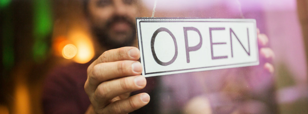 man flipping door sign to open on his bar