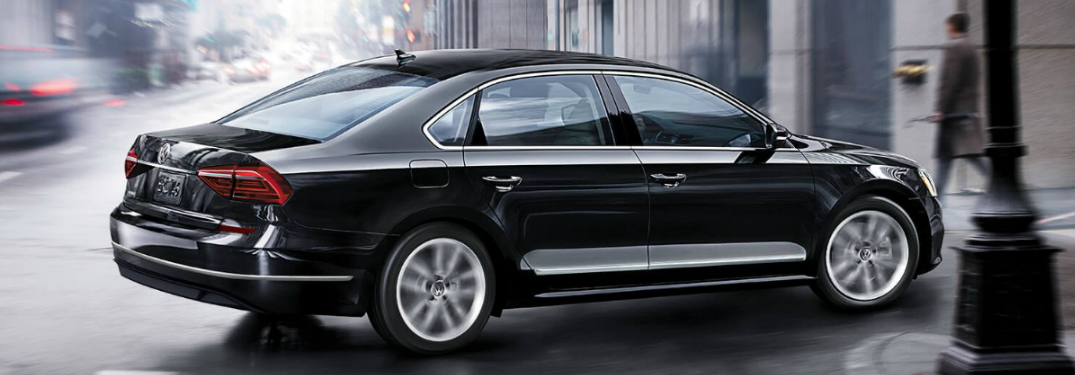 Black 2018 Volkswagen Passat Driving by a Light Pole on a City Street