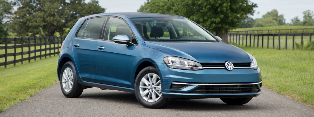 2018 Volkswagen Golf aqua teal exterior shot parked in the middle of a country road surrounded by green grass and wooden fences