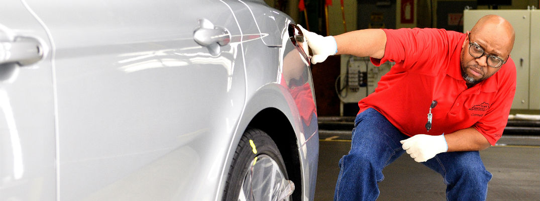 A photo of a Toyota official taking a very close look at a Toyota sedan
