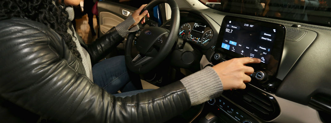 A photo of a person using the large touchscreen interface inside of the 2018 Ford EcoSport now available at Heritage Ford.