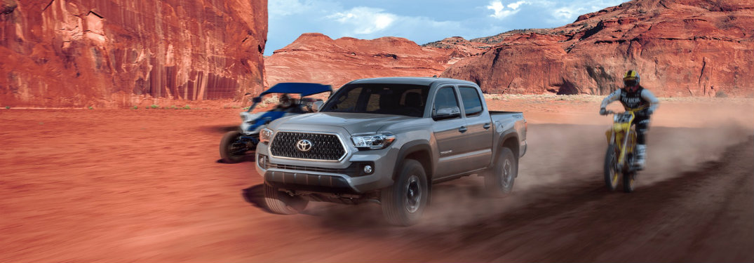 2018-Toyota-Tacoma-driving-on-desert-terrain-next-to-motorcycle-and-go-kart