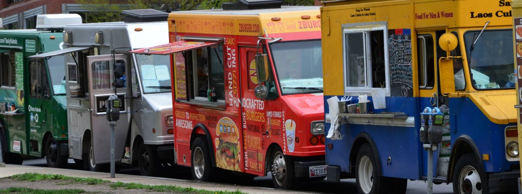 multiple food trucks lined up on the side of a road