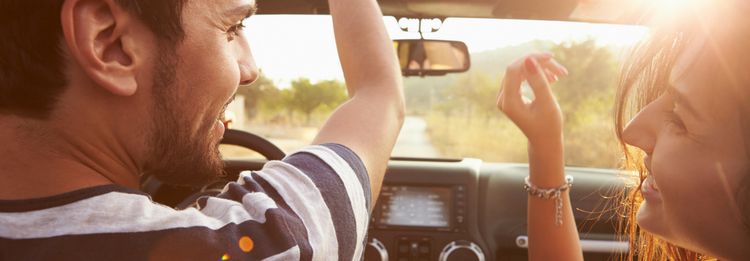 man-and-woman-with-hands-up-driving-in-convertible