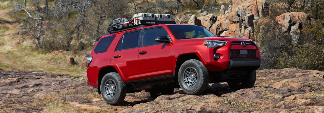 Red 2020 Toyota 4Runner Venture Edition driving over rocky terrain