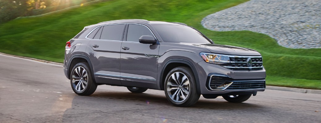 2020 Volkswagen Atlas Cross Sport dark grey driving around curve with green grass background