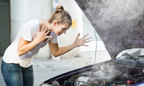 woman in white shirt and jeans stressed about overheated car