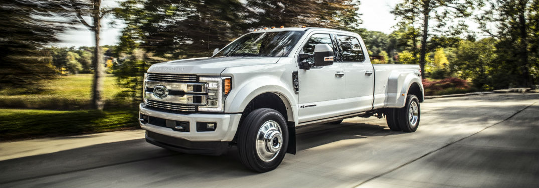 white 2018 Ford Super Duty Limited driving down a tree-lined street