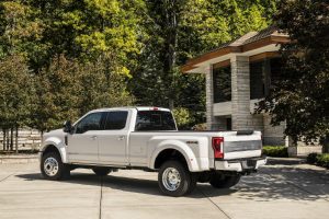 side view of a white 2018 Ford F-Series Super Duty Limited parked outside a house