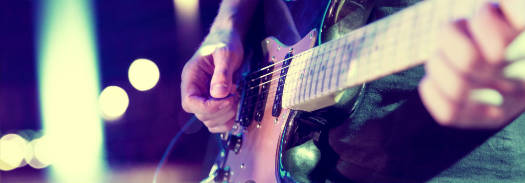 close up of hands playing a guitar