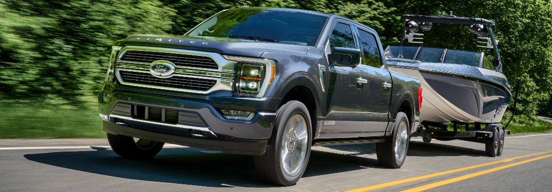 front view of a blue 2021 Ford F-150 towing a boat