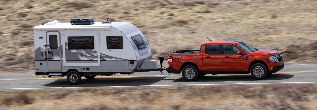 side view of a red 2022 Ford Maverick towing a camper