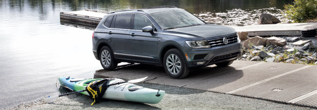 gray volkswagen tiguan with kayak on the ground