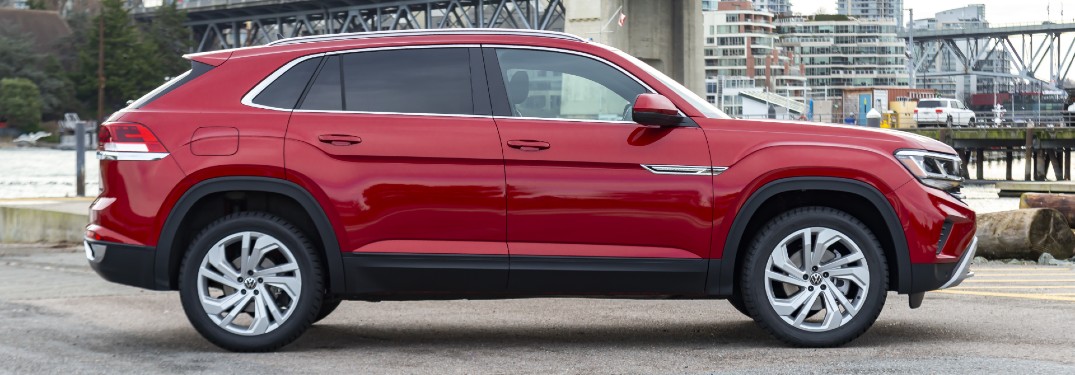 2020 Volkswagen Atlas Cross Sport exterior side shot with Aurora Red Metallic paint color parked on a concrete lot near a river