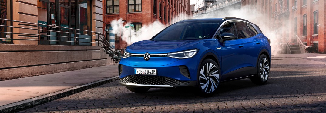 2021 Volkswagen ID.4 exterior shot with blue paint color parked on a cobblestone road with fog and brick buildings in the background