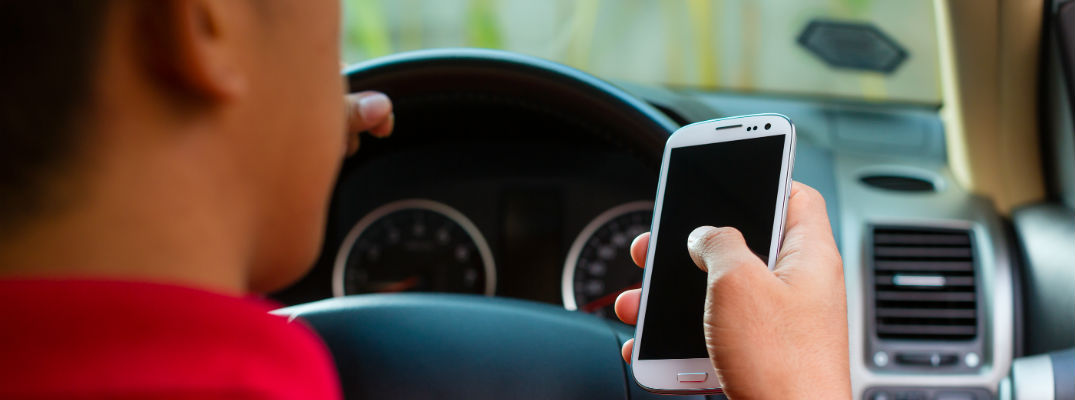 A stock photo of a man using a phone while driving.