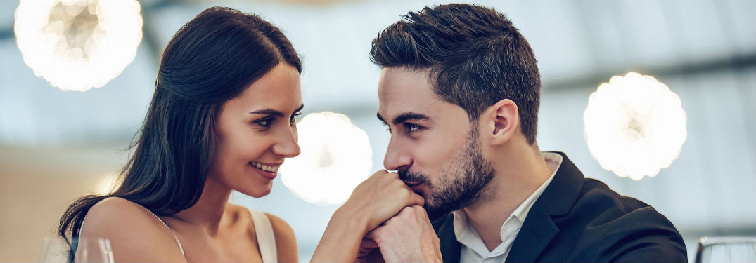 Man kissing woman's hand at dinner