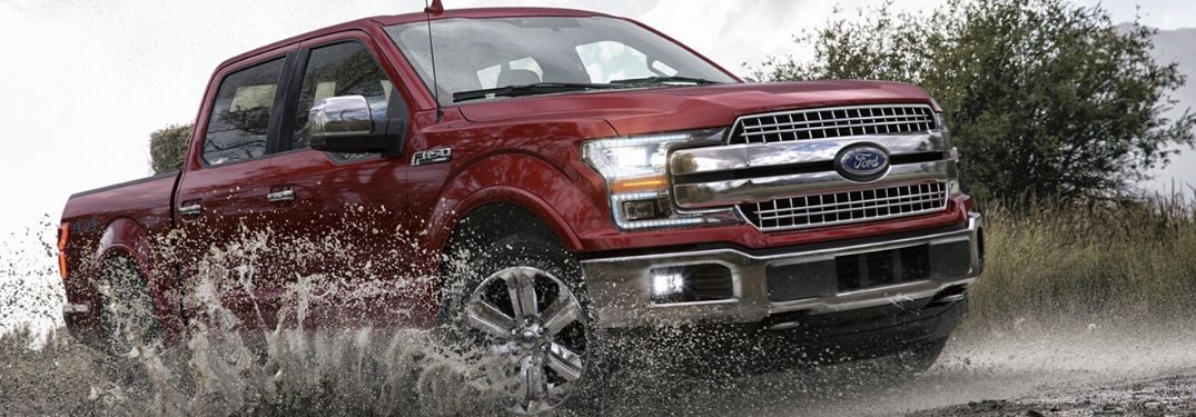 Red 2020 Ford F-150 driving through mud from exterior front passenger side