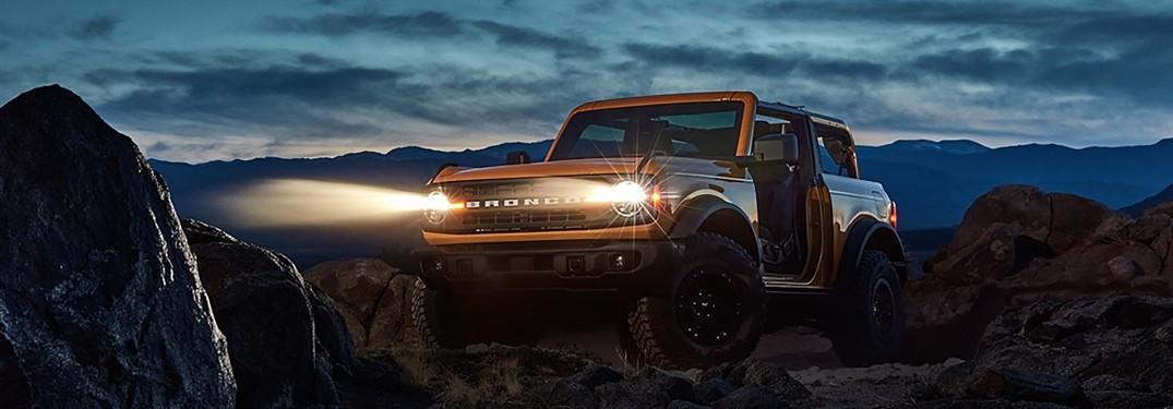 2021 Ford Bronco parked in desert with headlights on