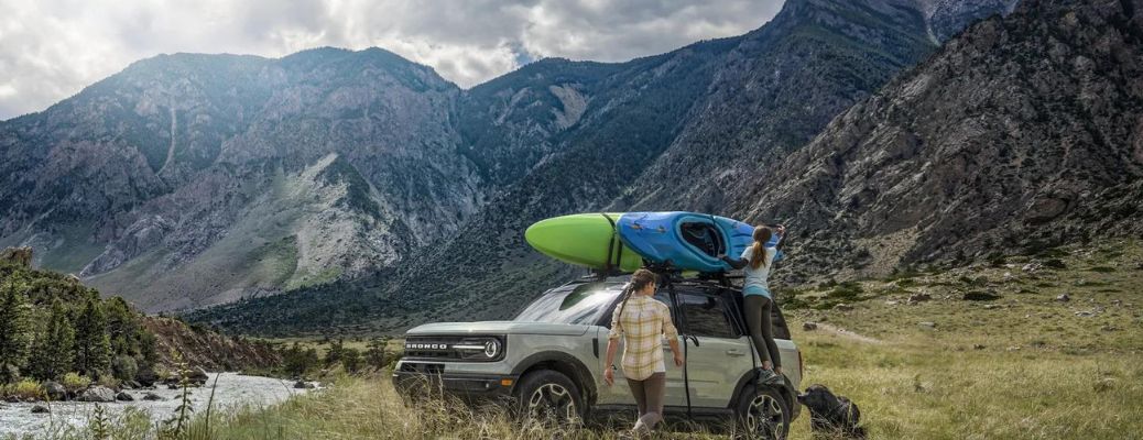 Couples setting up tent on their Ford