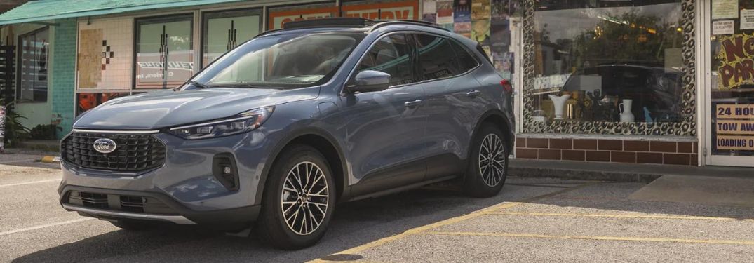 A grey 2023 Ford Escape parked in front of a shop.