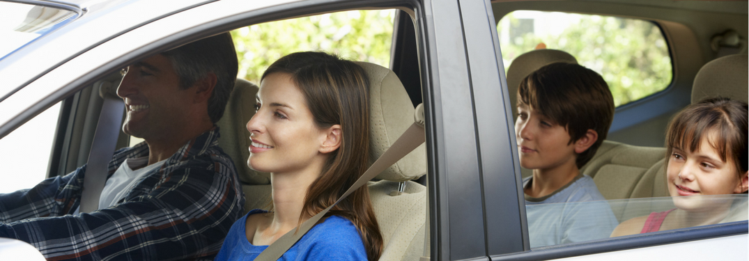 Family sitting in car happily