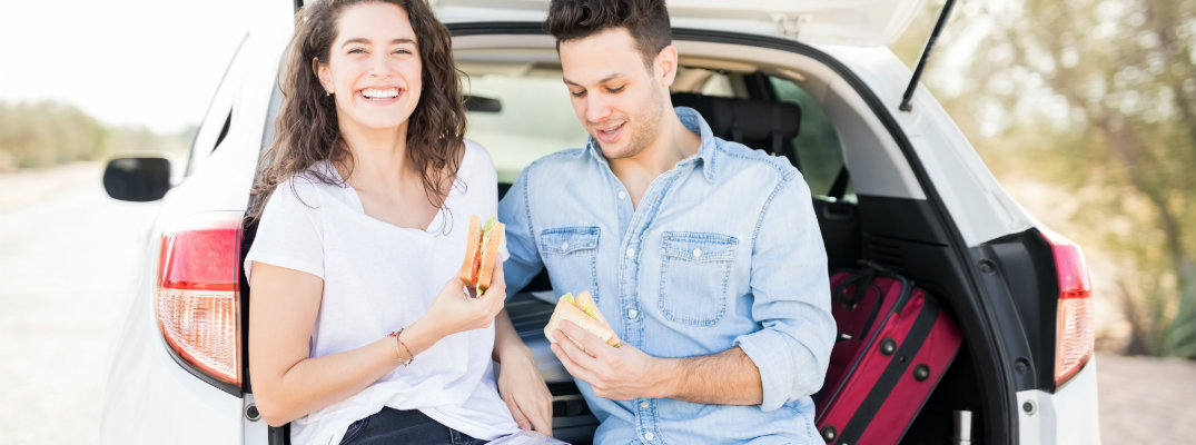 Couple eating snacks out of the boot of their vehicle