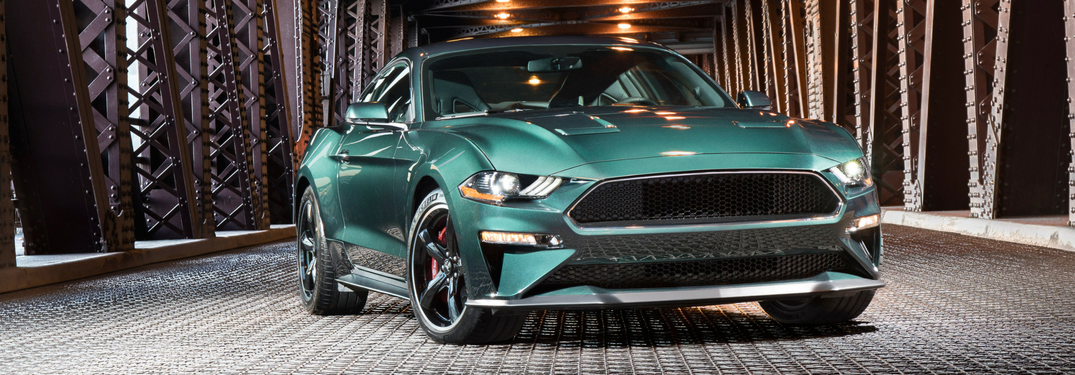 front and side view of green 2019 ford mustang bullitt on bridge