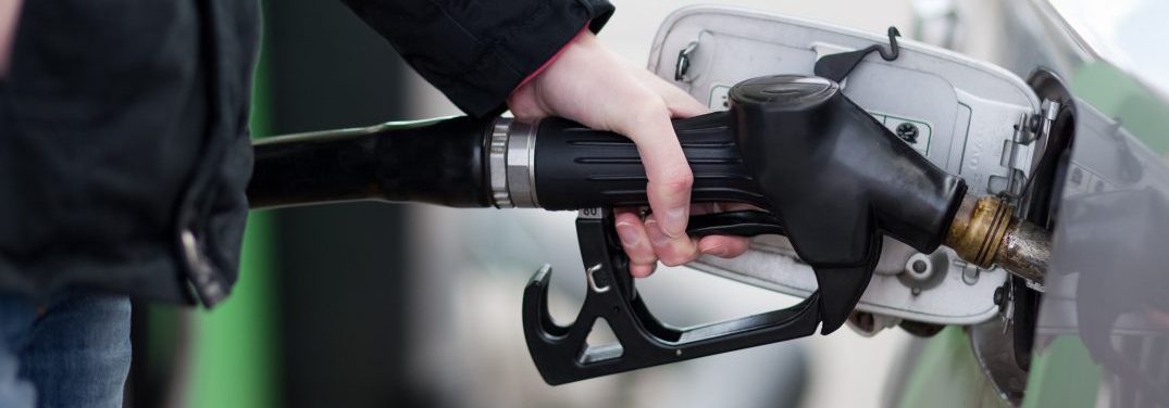 hand holding fuel pump to a car at a gas station