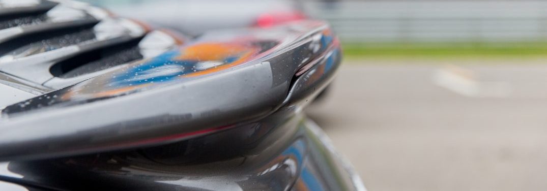 racing, motosports, extreme and motoring concept - close up of sports car back spoiler on speedway of stadium
