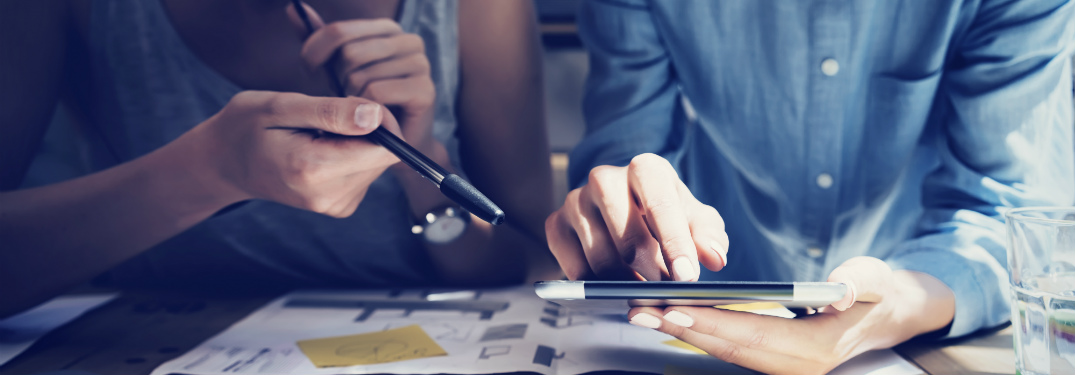 man and woman studying tablet with papers and notes strewn around