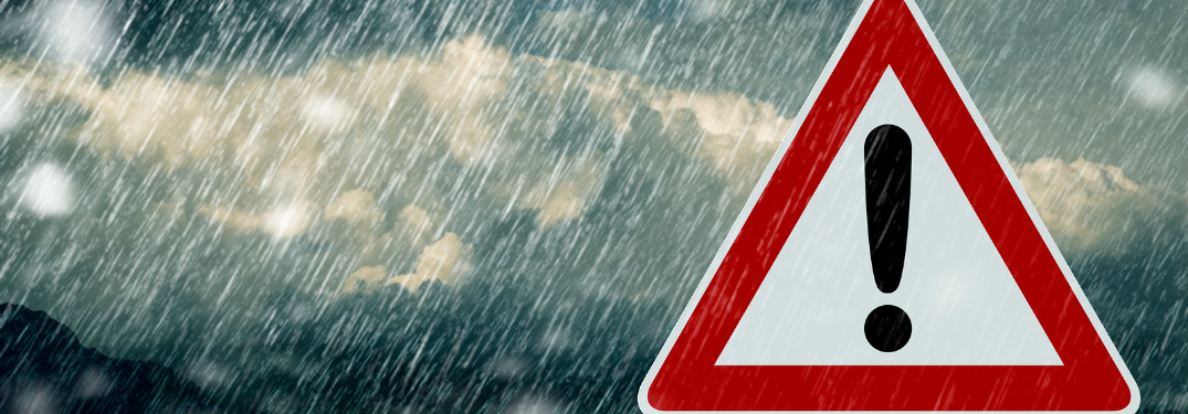 traffic sign with exclamation point with rain and storm clouds behind it