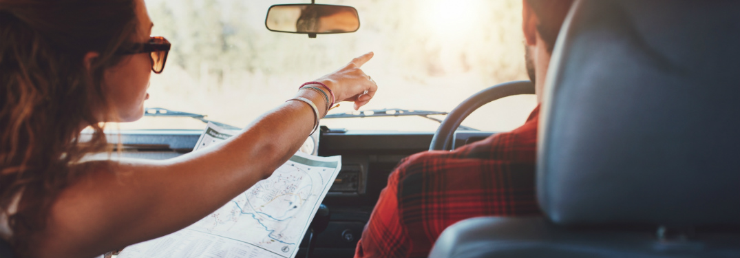 woman holding map in passenger seat and point for man driving