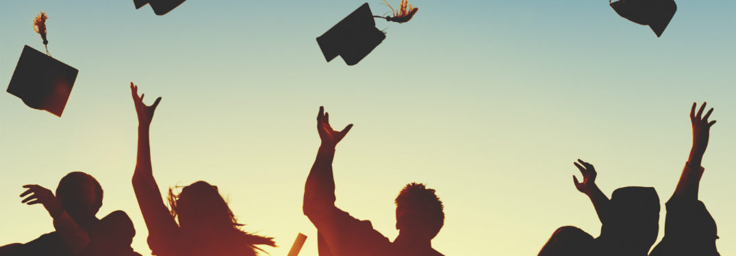 silhouettes of people in graduation gowns tossing caps in air