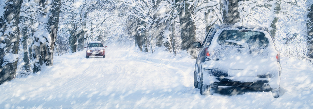 two cars driving past each other on road in snow storm