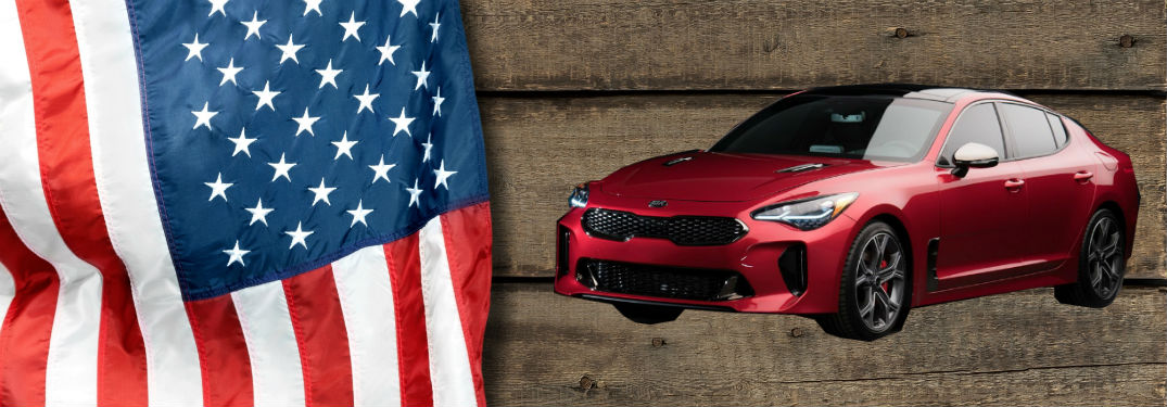 2018 Kia stinger alongside Ameircan flag on wood background