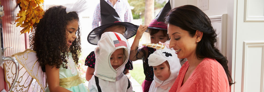 woman handing out trick-or-treat candy