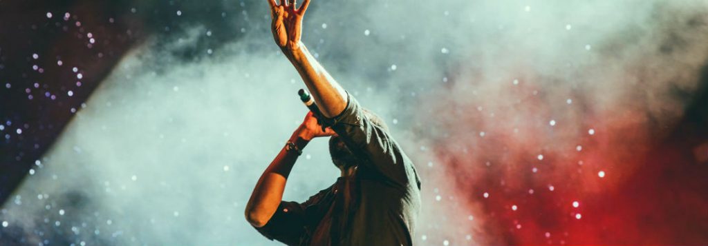 musician singing with hands raised