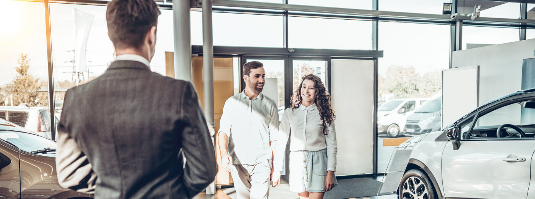 Couple walking towards salesman at dealership