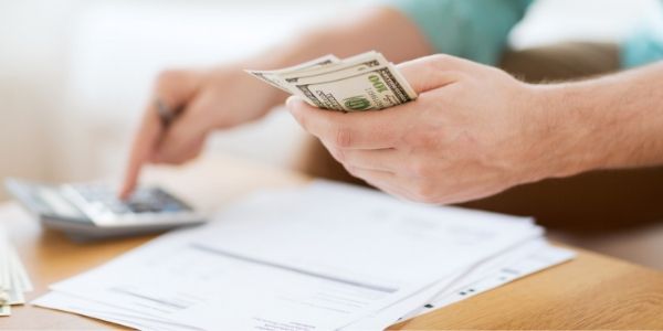 Hands counting money and using calculator