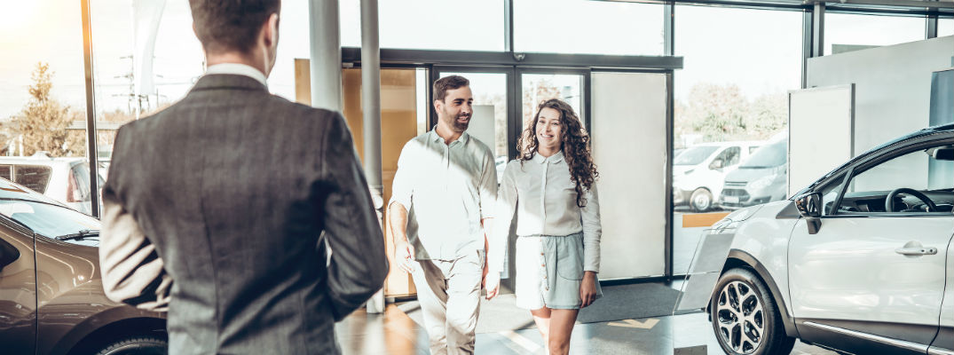 Man and woman walking into car dealership