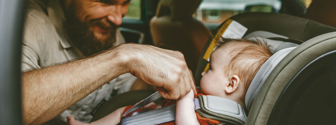 Man putting baby in car seat