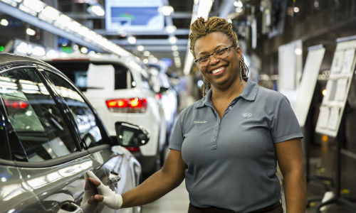 Kia Motors team member smiling and posing by vehicle