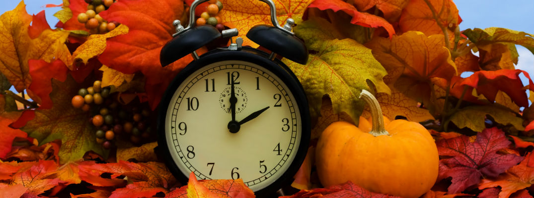 Alarm clock by pumpkin in fall scene